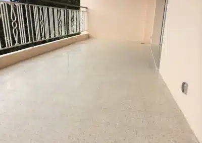 Terrasse en granito d'un immeuble du Cannet après ponçage, avec une finition poli-satiné, la balustrade à gauche et la porte-fenêtre à droite