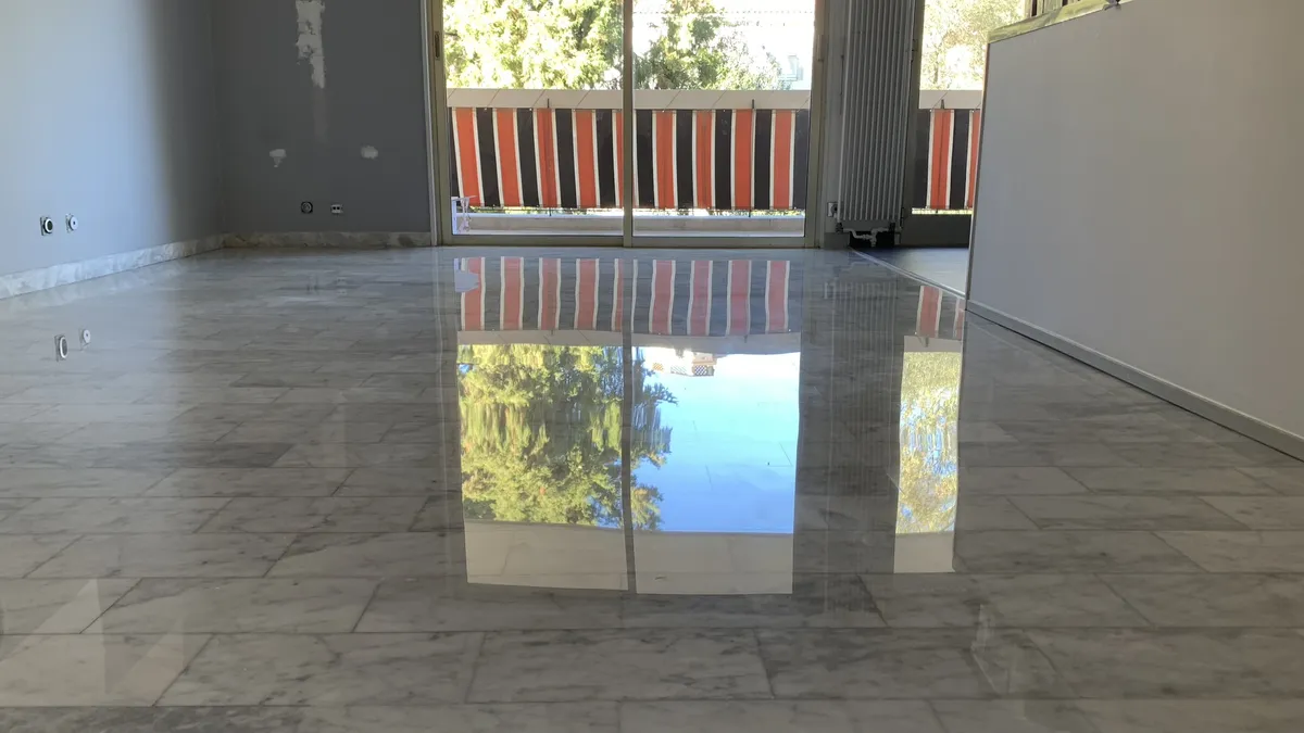marbre-blanc-de-carrare-poli-brillant-sejour-golfe-juan Séjour d'un appartement de Golfe-Juan avec un sol en marbre Blanc de Carrare poli-brillant reflétant la baie vitrée, le balcon et les arbres