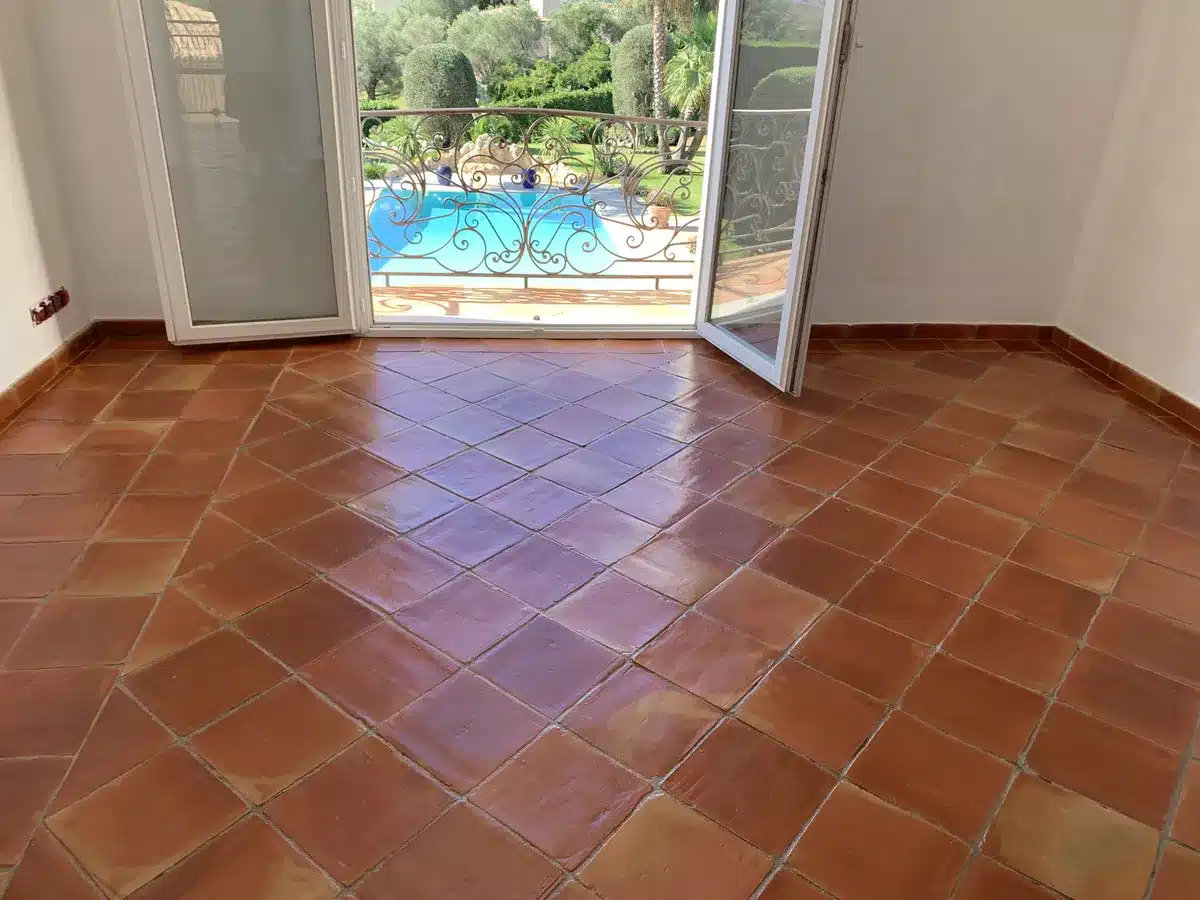 terre-cuite-cire-finition-satinee-chambre-etage-villa-mougins Chambre à l'étage d'une villa de Mougins avec une terre cuite rénovée, avec une finition satinée à la cire, la porte-fenêtre ouverte sur la piscine